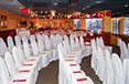 White covered chair decor with red accents and set tables in the background